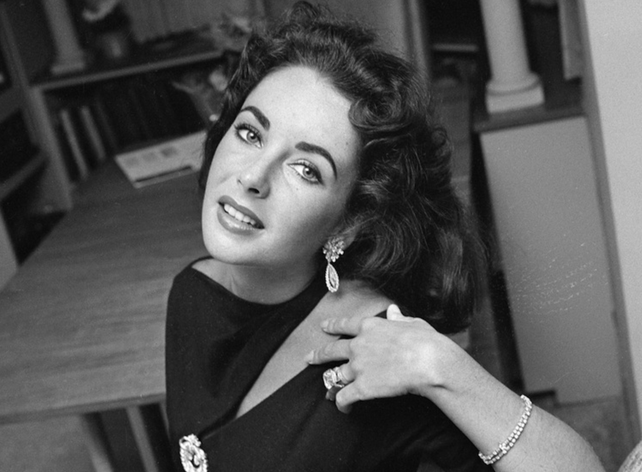 Elizabeth Taylor at home in a black dress, earrings, and a bracelet